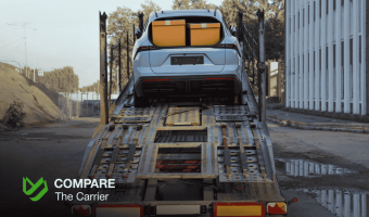 Silver SUV with two cardboard boxes on its roof being loaded onto an auto transport carrier, illustrating policies for car shipping with personal items